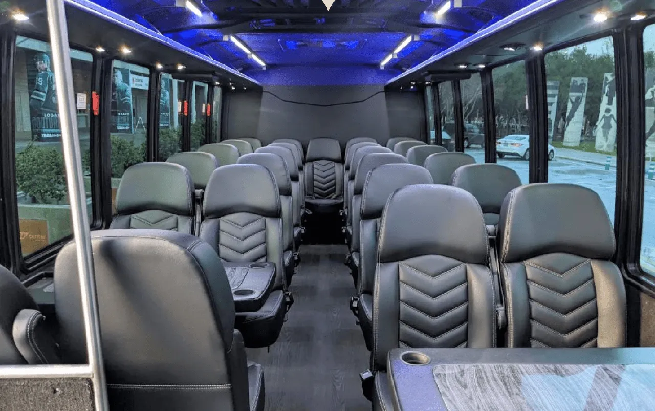 27 Passenger Mini Coach, the inside featuring passenger tables, cup holders and LED ceiling lighting