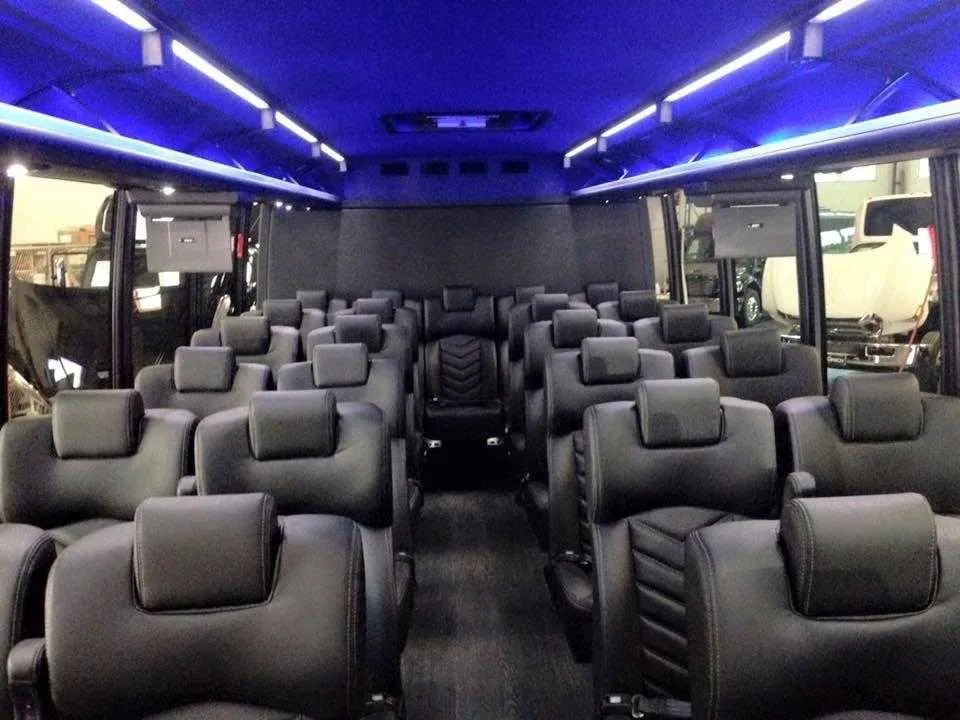 28 Passenger Mini Coach, the inside featuring airline-style seats, LED ceiling lighting and TV screens