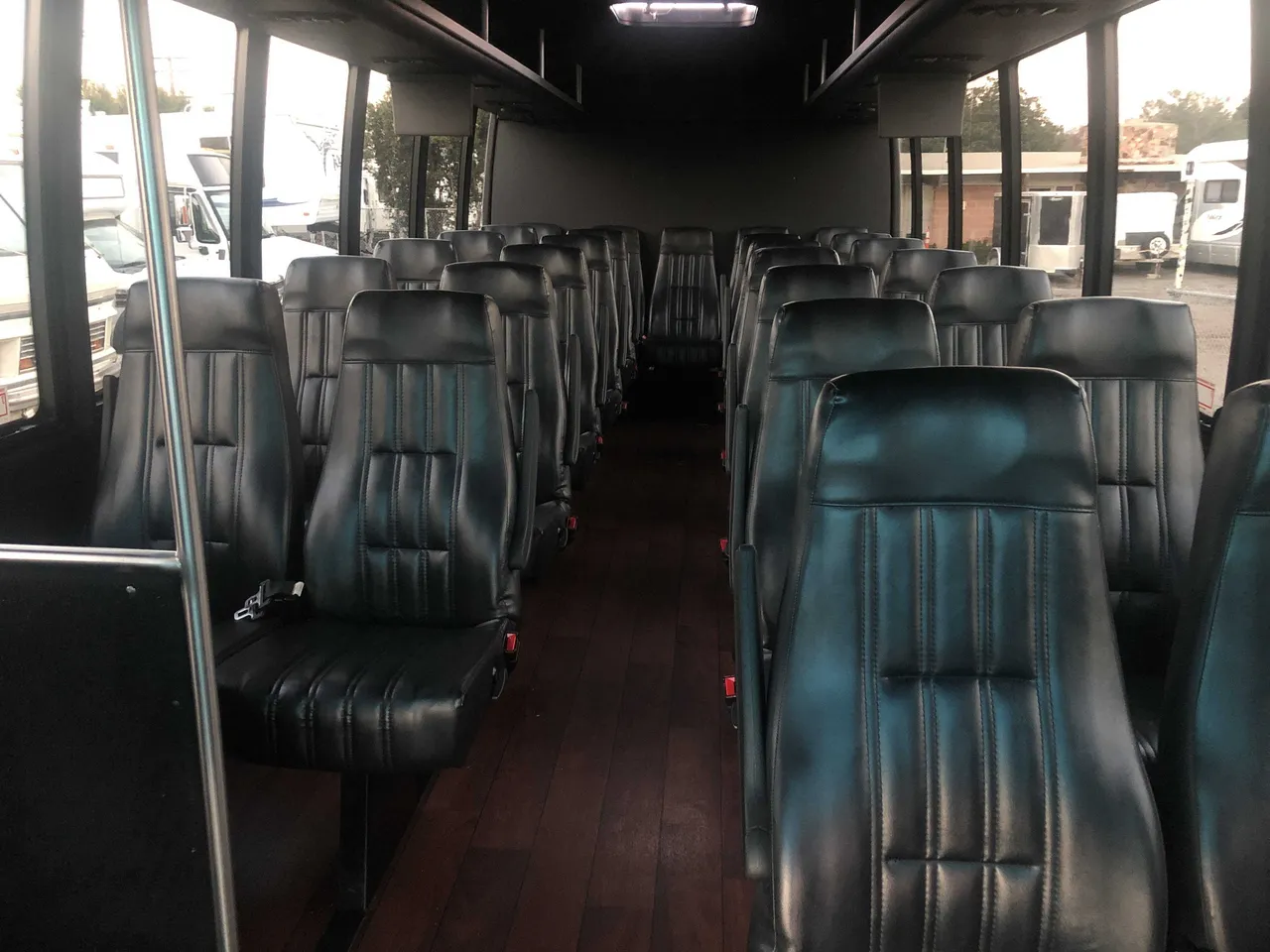 21 Passenger Mini Coach, the inside featuring airline-style seats, wood-look flooring and grab handles and rails