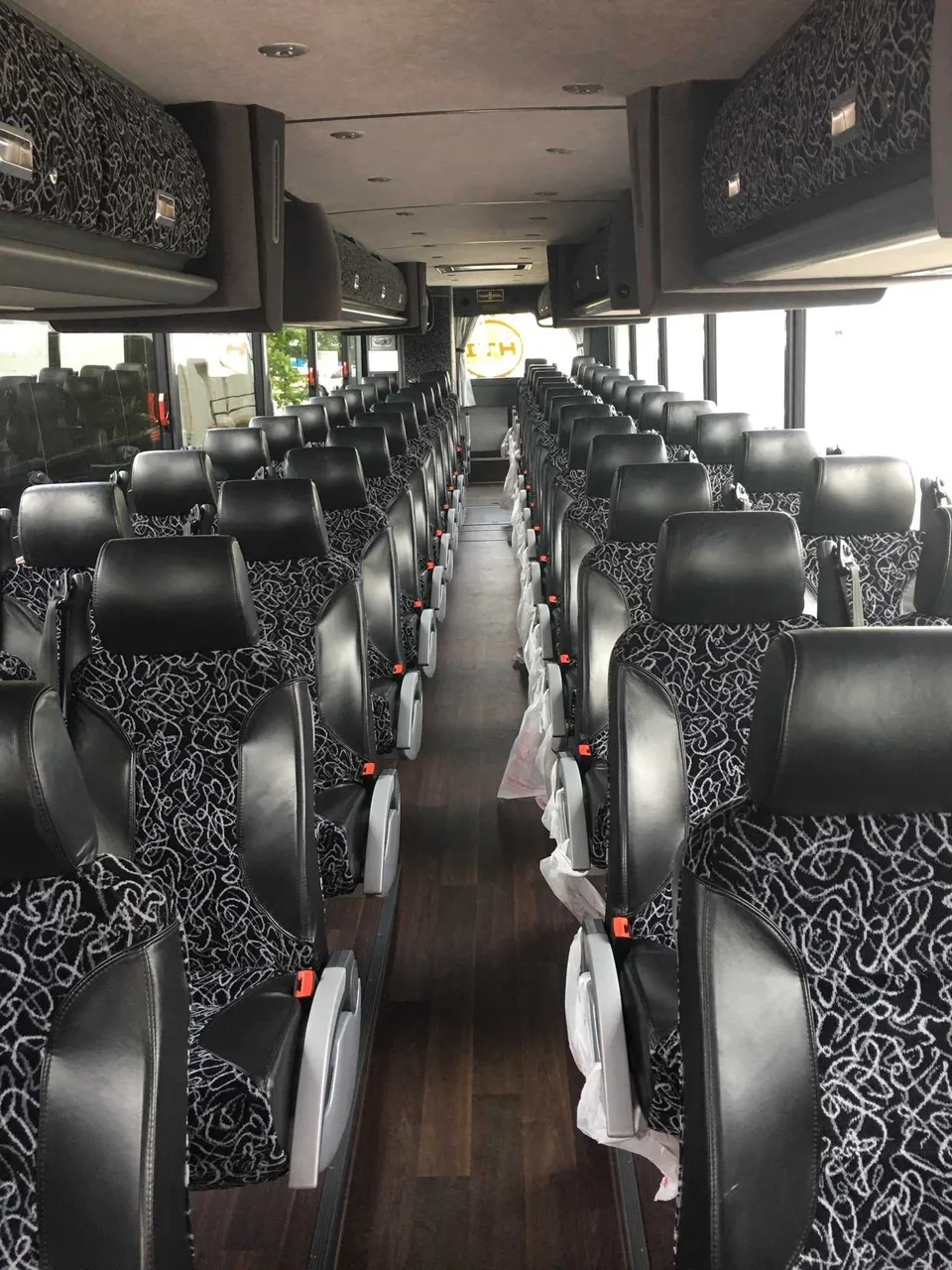 56 Passenger Motor Coach interior with passenger seat belts and overhead parcel racks for charter bus rental