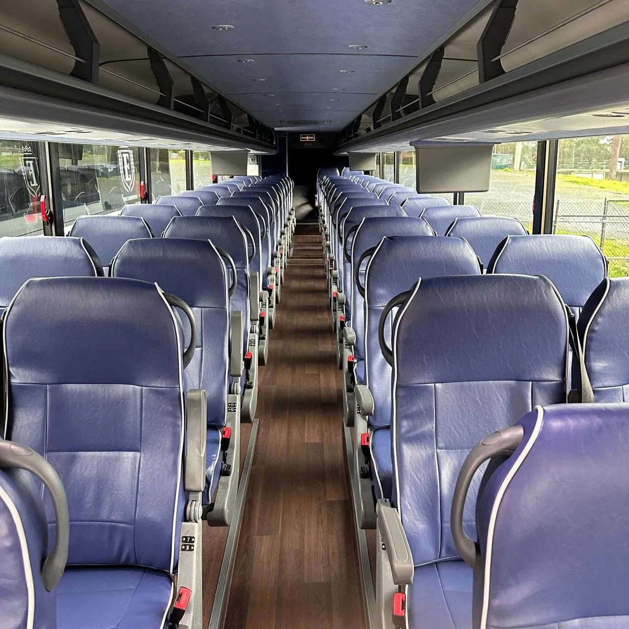 56 Passenger Motorcoach interior with passenger seat belts and overhead parcel racks for charter bus rental